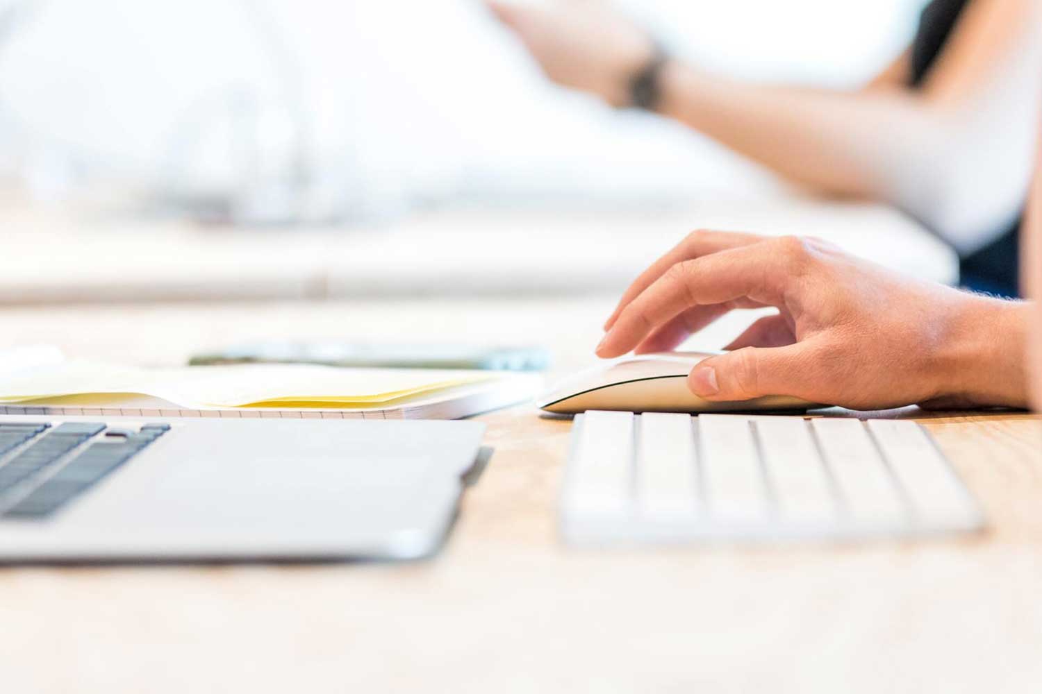 man's hand using mouse with a laptop