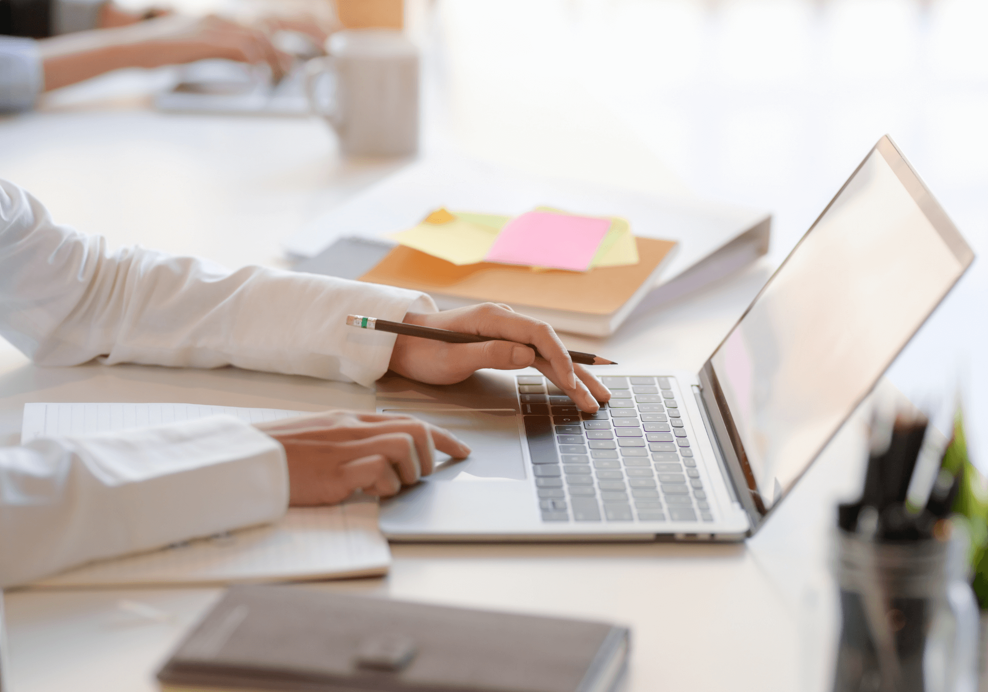man wearing a white shirt typing on macbook with post-it notes next to him